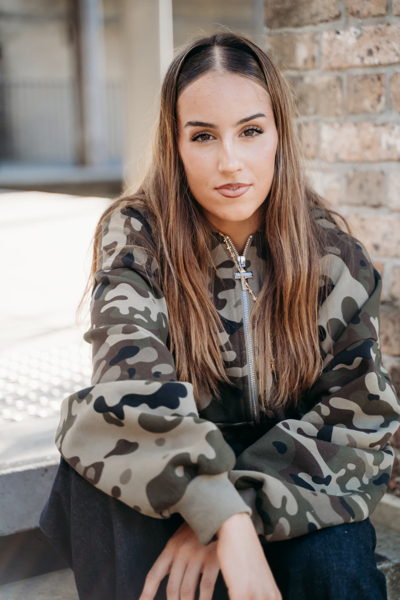 Summer-Rihana editorial — Camo hoodie · sunlit brick